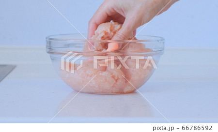 Girl is preparing minced meat. A female hand mixes the minced chicken and pork. Meat dishes 66786592
