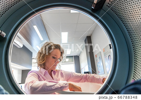 woman inserting clothes in a dryer in a public laundry woman inserting clothes in a dryer in a public laundry 66788348