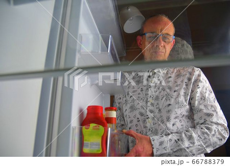 Portrait of a hungry man looking for food in refrigerator. Eating and diet concept - confused middle-aged man looking for food in empty fridge at kitchen 66788379