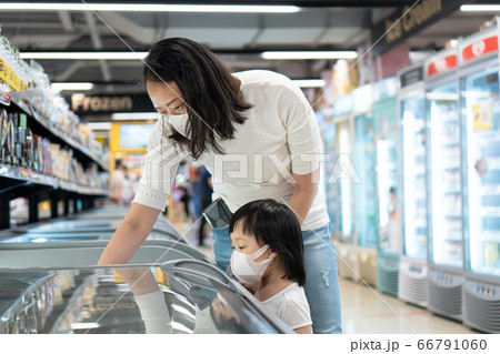 Young asian woman and 2 year old kid with face mask in supermarket. Young asian woman and 2 year old kid with face mask in supermarket. 66791060