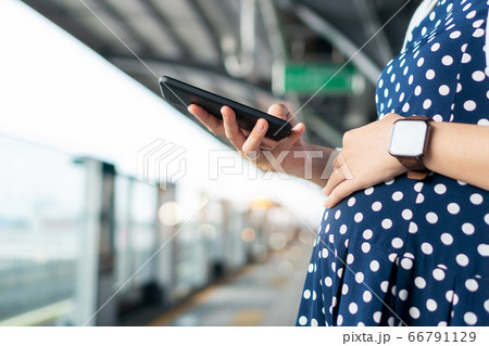 Pregnant woman using mobile phone while waiting commuter bus or train Pregnant woman using mobile phone while waiting commuter bus or train 66791129