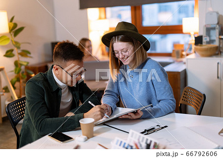 a group of young designers gathered in the evening in the office to discuss ideas a group of young designers gathered in the evening in the office to discuss ideas 66792606
