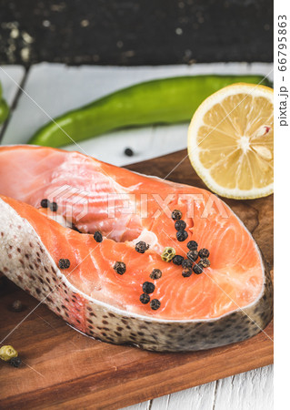 Salmon slices with black pepper balls and lemon on a wooden board Salmon slices with black pepper balls and lemon on a wooden board 66795863