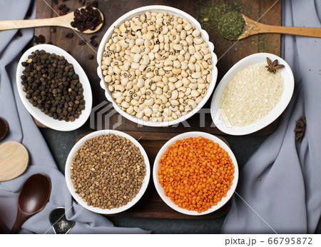 Red lentils, wheat, rice and buckwheat in a white bowl on a wooden board, top view 66795872