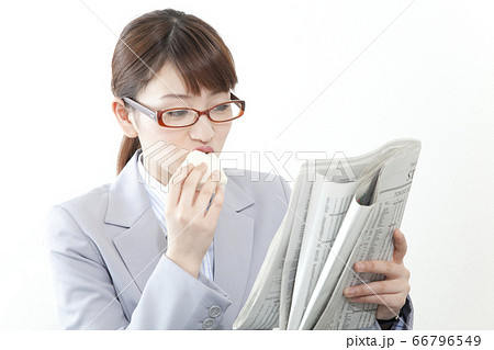 食事をしながら英字新聞を読むビジネスウーマン 食事をしながら英字新聞を読むビジネスウーマン 66796549