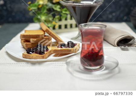 Toast slices with red jam and a glass of tea on the white table 66797330