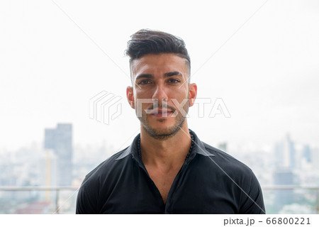 Face of young handsome bearded Persian businessman in the city outdoors 66800221