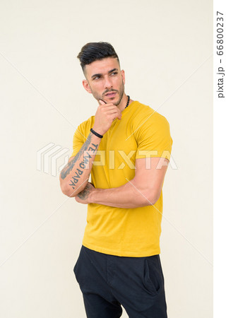 Young handsome bearded Persian man with tattoos thinking 66800237