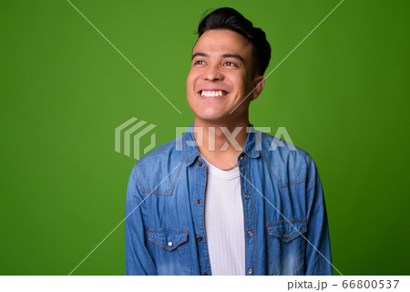 Young multi-ethnic man wearing smart clothing against green background 66800537