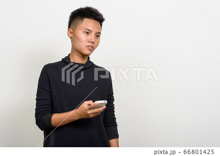 Portrait of young Asian lesbian woman thinking while using phone Portrait of young Asian lesbian woman thinking while using phone 66801425