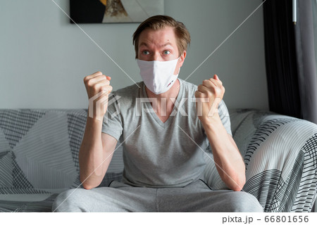 Young man with mask getting good news at home under quarantine 66801656