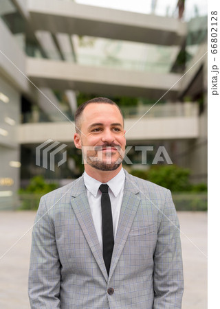 Handsome Hispanic bald bearded businessman thinking in the city outdoors Handsome Hispanic bald bearded businessman thinking in the city outdoors 66802128