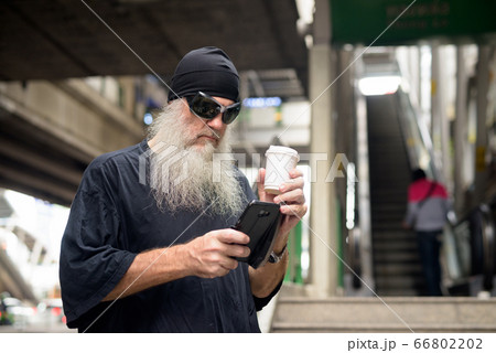 Mature bearded hipster man with sunglasses using phone in the city 66802202