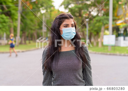 Young Indian woman with mask thinking at the park outdoors 66803280
