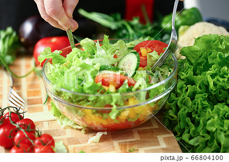 Young man mixing fresh salad with forks 66804100