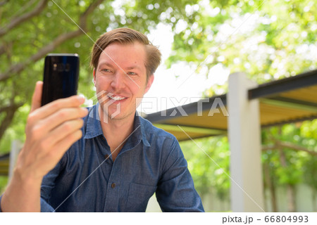 Face of happy young handsome blond businessman taking selfie at the park outdoors Face of happy young handsome blond businessman taking selfie at the park outdoors 66804993