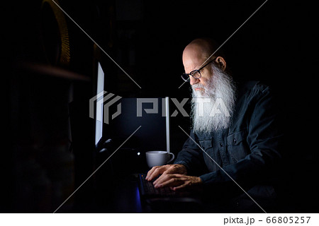 Mature bald bearded man working overtime at home in the dark Mature bald bearded man working overtime at home in the dark 66805257