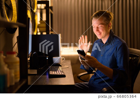 Happy young handsome businessman video calling while working from home at night 66805364