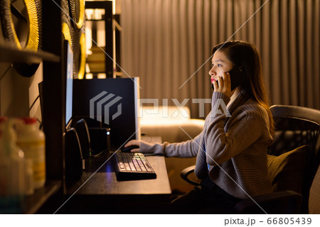 Young Asian woman talking on the phone while working from home Young Asian woman talking on the phone while working from home 66805439