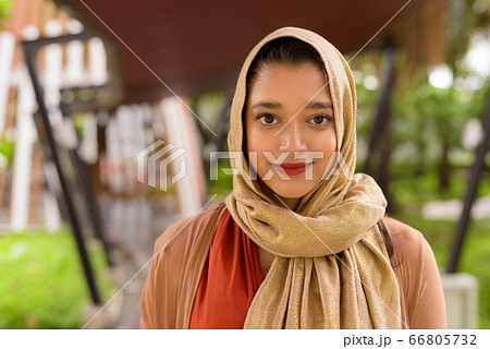 Face of young beautiful Indian Muslim woman in the city with nature Face of young beautiful Indian Muslim woman in the city with nature 66805732