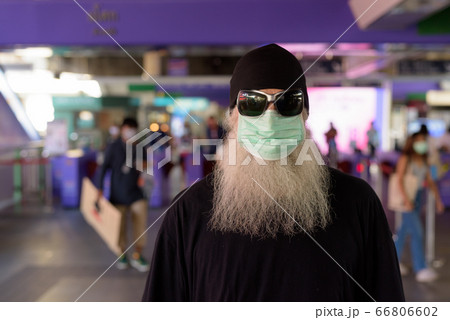 Face of mature bearded hipster man wearing mask and sunglasses at the sky train station 66806602