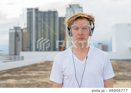 Young handsome man with face shield listening to music at rooftop of the building Young handsome man with face shield listening to music at rooftop of the building 66806777