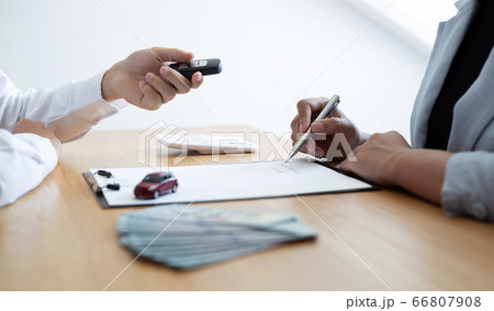 The car salesman handed the keys to the customer who passed the car purchase loan conditions ,Car rental agreement Concept. 66807908