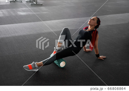 Woman massaging foam roll leg gym myofascial 66808864