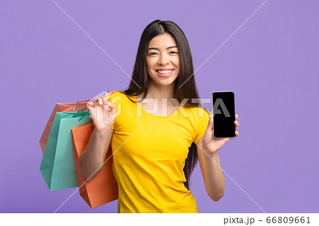 Shopping App. Asian Girl Holding Smartphone With Black Screen And Shopper Bags 66809661