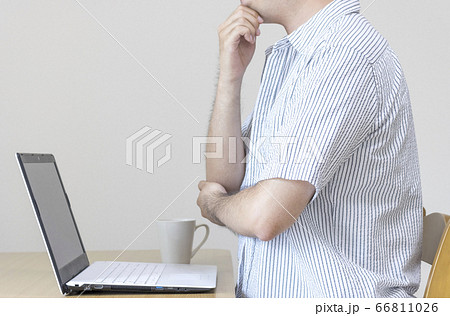 自宅で私服でノートパソコンで仕事をして考え事をしている男性 在宅勤務 副業のイメージの写真素材