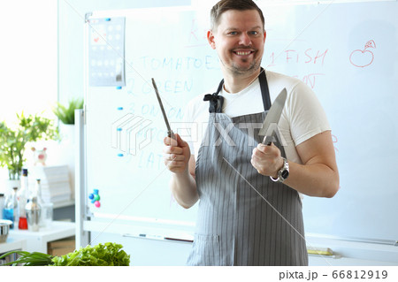 Joyful chef in apron holding kitchen knife Joyful chef in apron holding kitchen knife 66812919