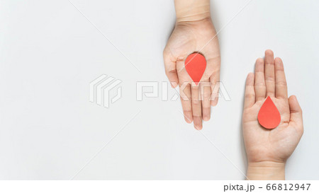 Blood donation - Human hand giving blood drop symbol to a hand on white background. World blood donor day and save life concept. Flat lay. Copy space. 66812947