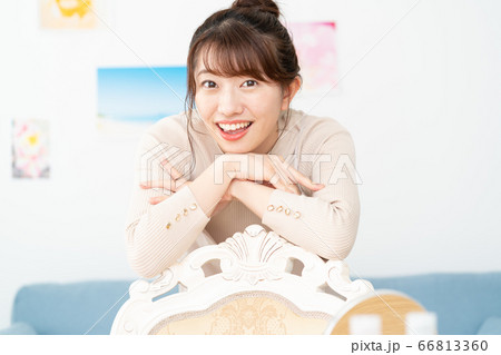 自宅のリビングでカメラ目線で微笑む若い女性のポートレート 66813360