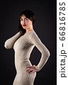 Woman in beige tight dress on black 66816785