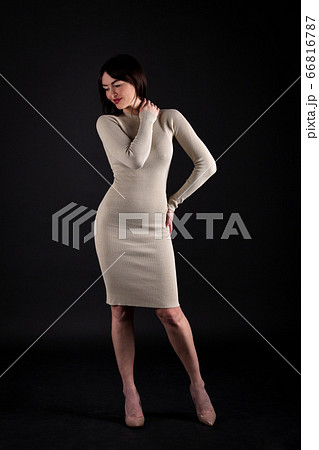 Woman in beige tight dress on black 66816787
