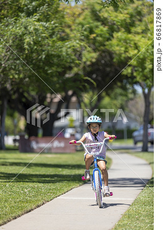 公園の歩道をサイクリングする女の子 海外 の写真素材 公園の歩道をサイクリングする女の子 海外 の写真素材