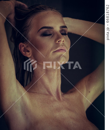 Relaxation and spa concept. Portrait of a sexy fashionable lady in a black swimsuit. Woman with wet hair and makeup poses in shower near swimming pool in natural light 66818762