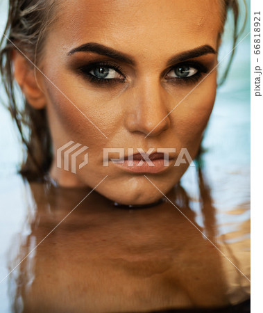 Relaxation and spa concept. Portrait of a sexy fashionable lady in a black swimsuit. Woman with wet hair and makeup poses in water in swimming pool in natural sunlight Relaxation and spa concept. Portrait of a sexy fashionable lady in a black swimsuit. Woman with wet hair and makeup poses in water in swimming pool in natural sunlight 66818921