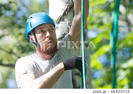 Rope adventure - man in blue helmet holding by the rope 66820358