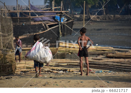 バングラデシュのコックスバザール　海岸沿いの漁村と停留中の漁船　砂浜を歩いて資源ゴミを集める少年 66821717