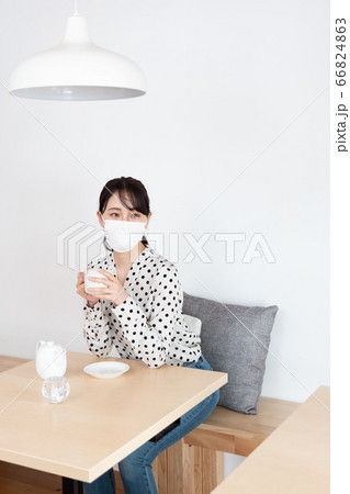 マスクをつけてカフェでお茶を飲んでいる女性 66824863