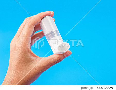Person holding a white asthma inhaler. Person holding a white asthma inhaler. 66832729