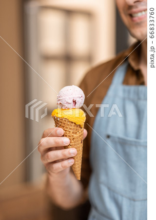 Seller with ice cream in a waffle cone, close-up 66833760