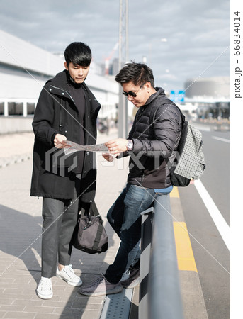 Young men find the way to travel in the city by looking on paper map 66834014