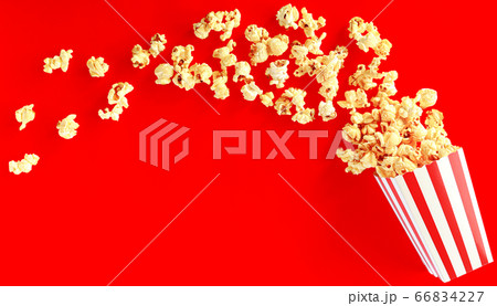 popcorn in classic bucket red and white splashing out of the box 66834227