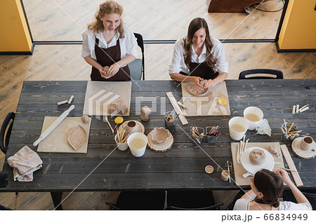 Female potters during the working process in the clay workshop. Woman masters prepare ceramic and clay products at big wooden table 66834949