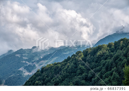 High mountain with green slopes hidden in clouds and fog High mountain with green slopes hidden in clouds and fog 66837391