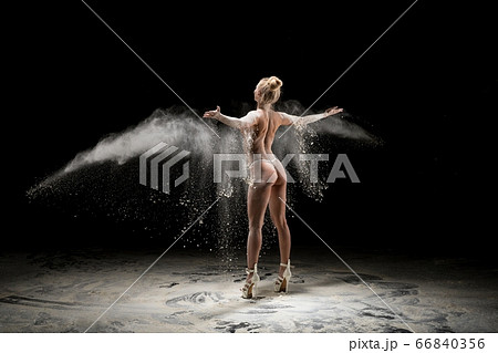 Anonymous topless woman throwing sand in air 66840356