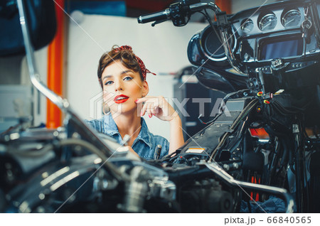 beautiful girl posing repairs a motorcycle in a 66840565