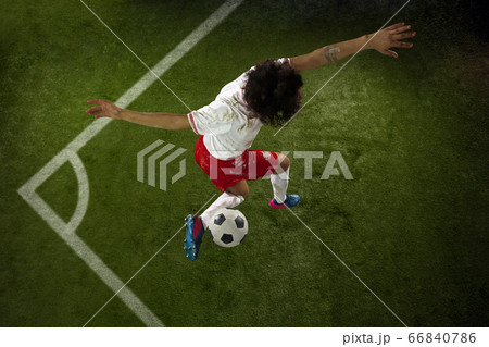 Top view of caucasian football or soccer player on green background of grass in action and motion Top view of caucasian football or soccer player on green background of grass in action and motion 66840786